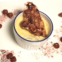 Image of a ramekin of candy cane creme brule topped with a piece of hazelnut brittle