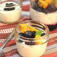Image of A mason jar of the buttermilk panna cotta topped with blueberries and some cornbread