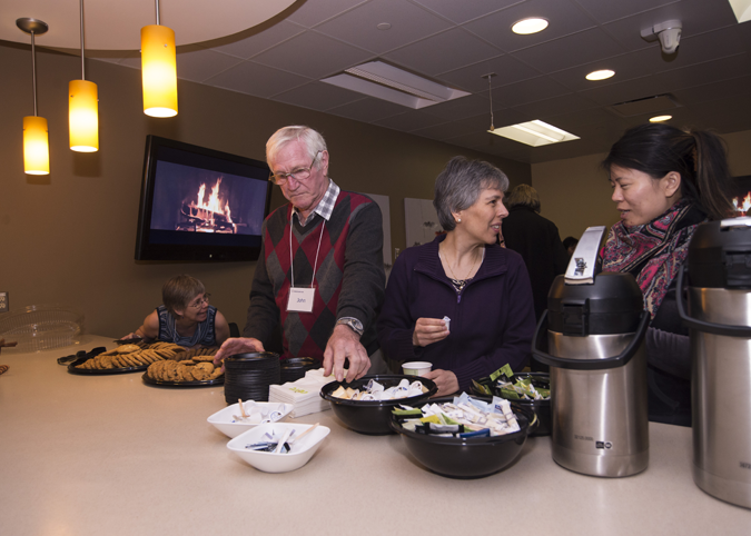 a man and three women standing at a counter, having coffee