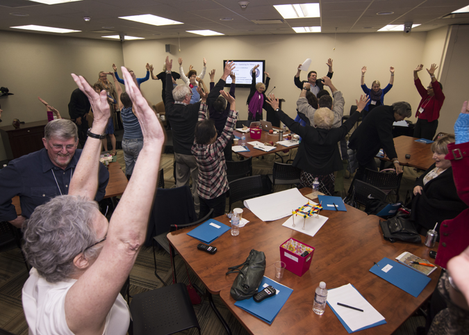 a room full of people, standing with their arms over in the air