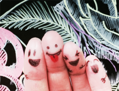 Image of smiley faces drawn on someone's fingers